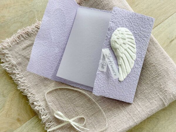 Geöffnete Ansicht Glückwunschkarte aus handgeschöpftem Papier mit weissen Engelsflügeln auf lila Karte im Gatefold Design. Personalisierbar, hergestellt in meiner kleinen Manufaktur in der Schweiz.