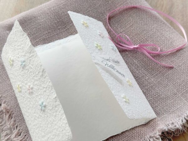 Geöffnete Gatefold Karte aus handgeschöpftem Papier mit geprägten Blümchen, handbemalt in zarten pastell Farben.