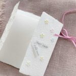 Geöffnete Gatefold Karte aus handgeschöpftem Papier mit geprägten Blümchen, handbemalt in zarten pastell Farben.