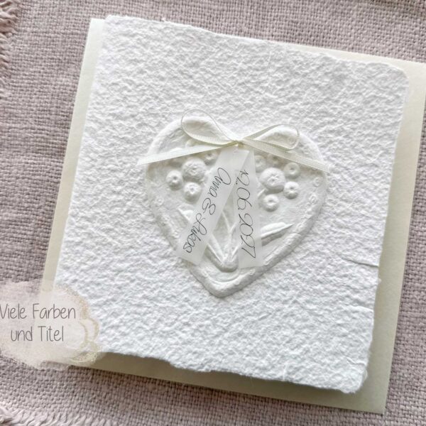 Personalisierte Hochzeitseinladung "Büttenherz" aus handgeschöpftem Papier weiss in weiss. Mit personalisiertem Titel auf zwei transparentpapierstreifen.