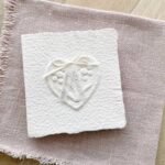 Handgemachte Hochzeitseinladung "Büttenherz" aus handgeschöpftem Papier weiss in weiss. Mit Namen des Brautpaares als Titel.