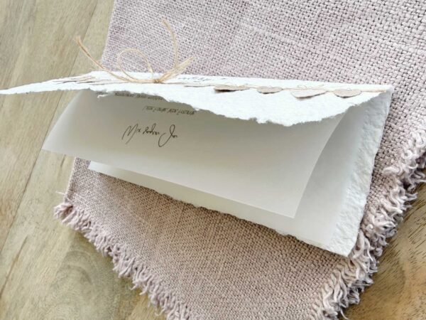 Hochzeitseinladung aus handgeschöpftem Papier mit weichem Büttenrand und einer Wimpelkette aus kleinen Herzen