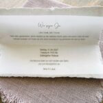 Aufgeklappte Hochzeitseinladung aus Büttenpapier mit bedrucktem Einlegeblatt