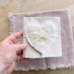 Grössenansicht Hochzeitseinladung aus handgeschöpftem Papier mit edlem, handgefilztem Perlenherz als Motiv. Gatefold Design mit Satinband verschlossen.
