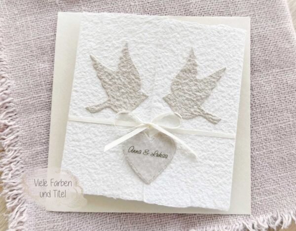 Exklusive Hochzeitseinladung «Tauben» aus handgeschöpftem Büttenpapier im Gatefold Desing mit zwei beigen Tauben und elegantem Satinband. Personalisierter Titel auf beigem Herz.