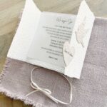 Geöffnete Ansicht einer Hochzeitseinladung «Tauben» aus handgeschöpftem Büttenpapier im Gatefold Desing mit zwei beigen Tauben und elegantem Satinband. Mit Beispieltext für bedrucktes Einlegeblatt