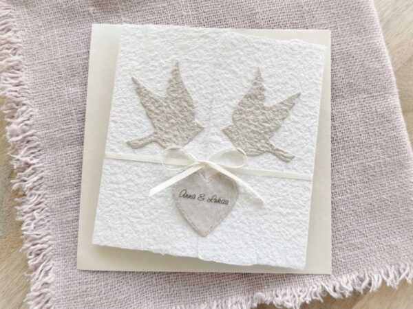 Hochzeitseinladung «Tauben» aus handgeschöpftem Büttenpapier im Gatefold Desing mit zwei beigen Tauben und elegantem Satinband. Personalisierter Titel auf beigem Herz.