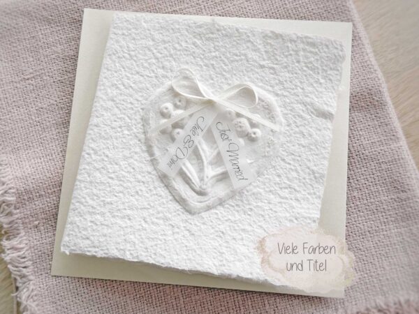 Personalisierte Glückwunschkarte zur Hochzeit aus handgeschöpftem Papier. Mit einem 3D-Herz aus einem Springerle Herz, welches zwei Blumen aus einer Wurzel zeigt. In der edlen Hochzeitskombination "weiss in weiss".