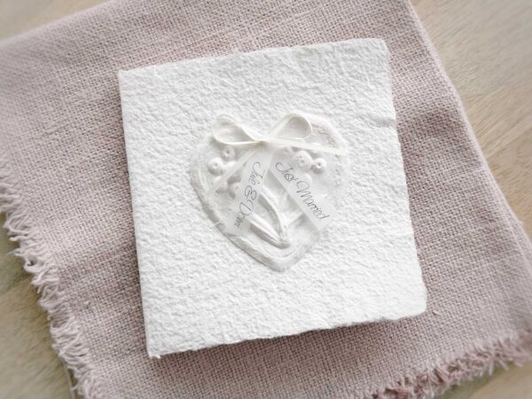Glückwunschkarte zur Hochzeit aus handgeschöpftem Papier. Mit einem 3D-Herz aus einem Springerle Herz, welches zwei Blumen aus einer Wurzel zeigt. In der edlen Hochzeitskombination "weiss in weiss".