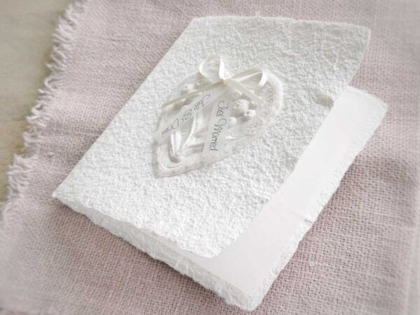 Geöffnete Ansicht Glückwunschkarte zur Hochzeit aus handgeschöpftem Papier. Mit einem 3D-Herz aus einem Springerle Herz, welches zwei Blumen aus einer Wurzel zeigt. In der edlen Hochzeitskombination "weiss in weiss".