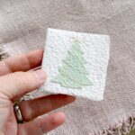 Kleine Weihnachtskarte Tannenbaum aus handgeschöpftem Papier in einer Hand – Format ca. 6,5 × 6,5 cm