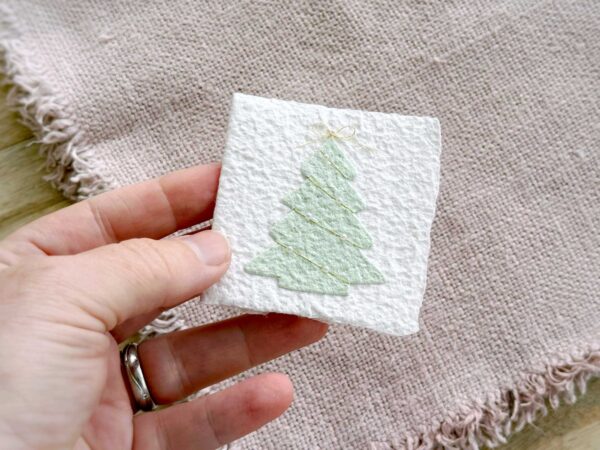Kleine Weihnachtskarte Tannenbaum aus handgeschöpftem Papier in einer Hand – Format ca. 6,5 × 6,5 cm