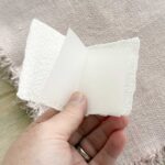 Geöffnete Mini-Weihnachtskarte aus handgeschöpftem Papier mit gefaltetem Transparent-Einlegeblatt für persönliche Grüsse