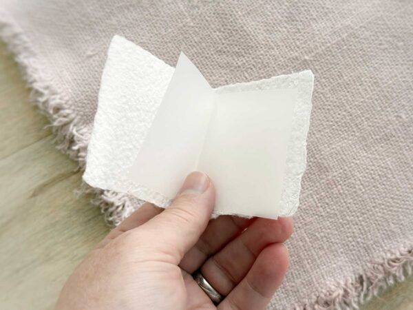 Geöffnete Mini-Weihnachtskarte aus handgeschöpftem Papier mit gefaltetem Transparent-Einlegeblatt für persönliche Grüsse