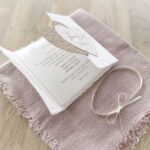 Aufgeklappte Ansicht einer Gatefold-Hochzeitseinladung mit bedrucktem Einlegeblatt. Mit zwei beigen Herzen mit personalisiertem Titel.