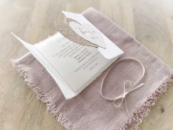 Aufgeklappte Ansicht einer Gatefold-Hochzeitseinladung mit bedrucktem Einlegeblatt. Mit zwei beigen Herzen mit personalisiertem Titel.