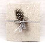 Trauerkarte aus handgeschöpftem Papier in beige mit einer Feder, Titelstreifen und Satinschleifchen