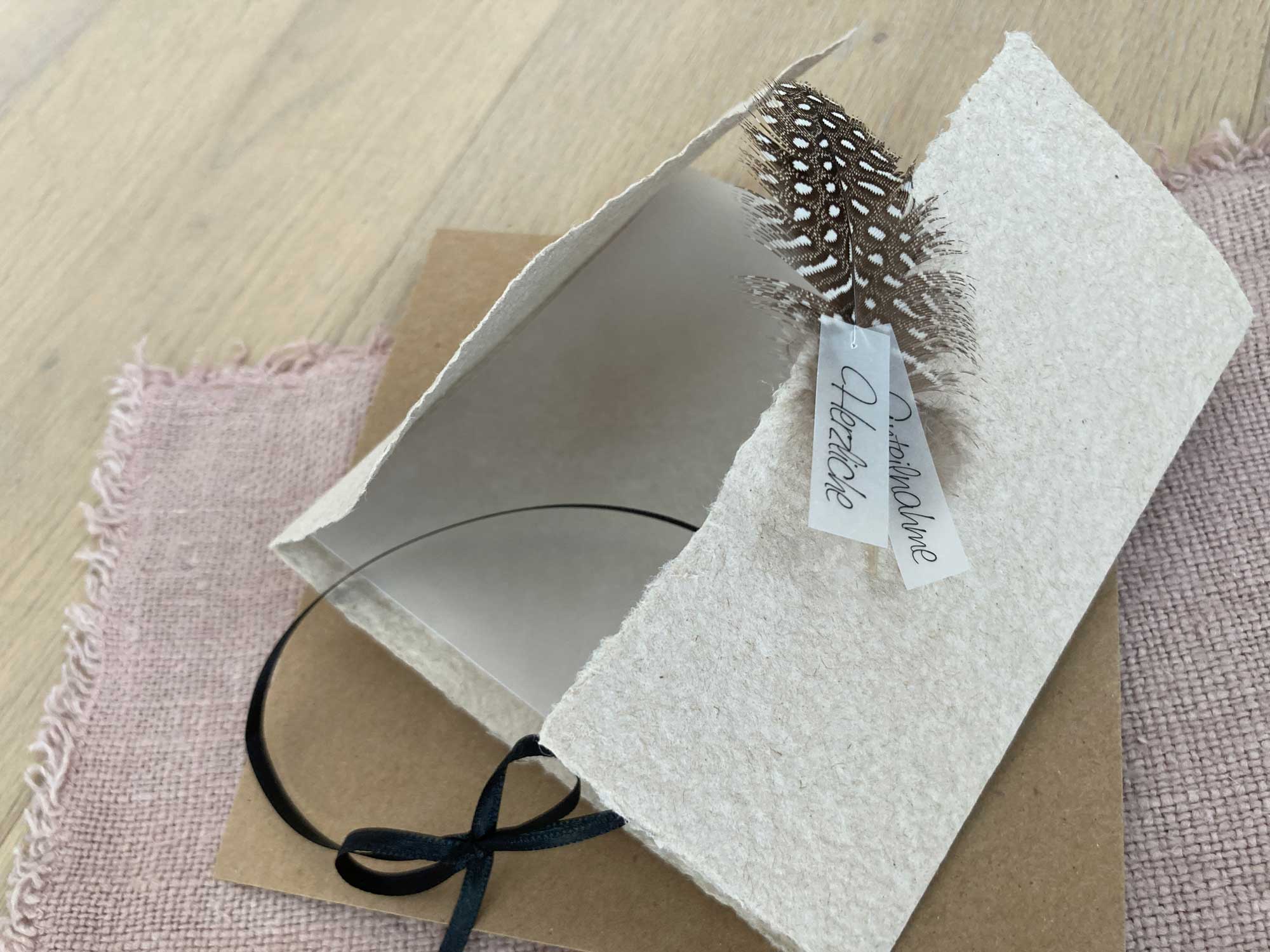 Geöffnete Ansicht der handgeschöpften Trauerkarte "Feder" im Gatefold Design mit echter Perlhuhnfeder