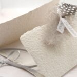 Trauerkarte aus handgeschöpftem Papier in beige mit einer Feder, Titelstreifen und Satinschleifchen