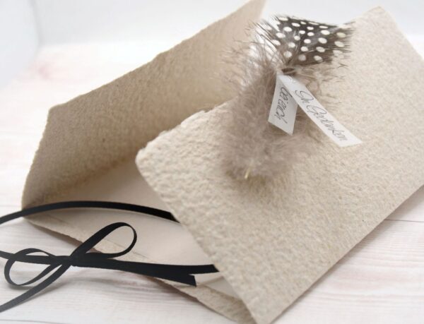 Trauerkarte aus handgeschöpftem Papier in beige mit einer Feder, Titelstreifen und Satinschleifchen