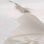 Trauerkarte aus handgeschöpftem Papier in weiss mit einer Feder, Titelstreifen und Satinschleifchen
