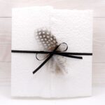Trauerkarte aus handgeschöpftem Papier in weiss mit einer Feder, Titelstreifen und Satinschleifchen