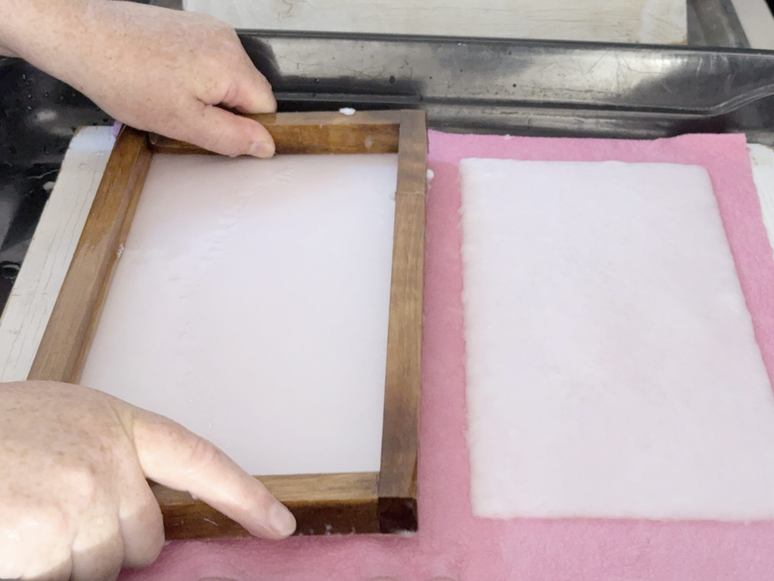 Übertragen des Papiers auf ein Tuch Frisch handgeschöpftes Papier wird von Hand auf ein Tuch übertragen