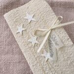 Detailaufnahme personalisierte Weihnachtskarte beige aus handgeschöpftem Papier mit Sternli, Gold und Perlenglanz