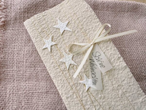 Detailaufnahme personalisierte Weihnachtskarte beige aus handgeschöpftem Papier mit Sternli, Gold und Perlenglanz