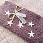 Nahaufnahme Weihnachtskarte mauve aus handgeschöpftem Papier mit Sternli, Gold und Perlenglanz