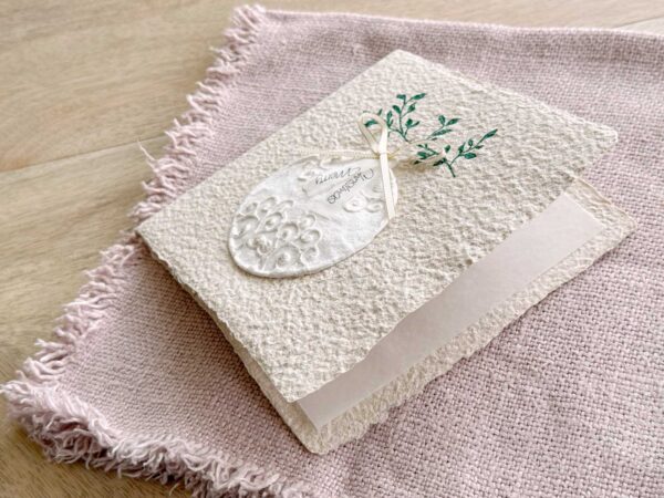 Leicht geöffnete, personalisierbare Weihnachtskarte aus beigem Büttenpapier mit barocker Weihnachtskugel und zart glänzenden Gold Details